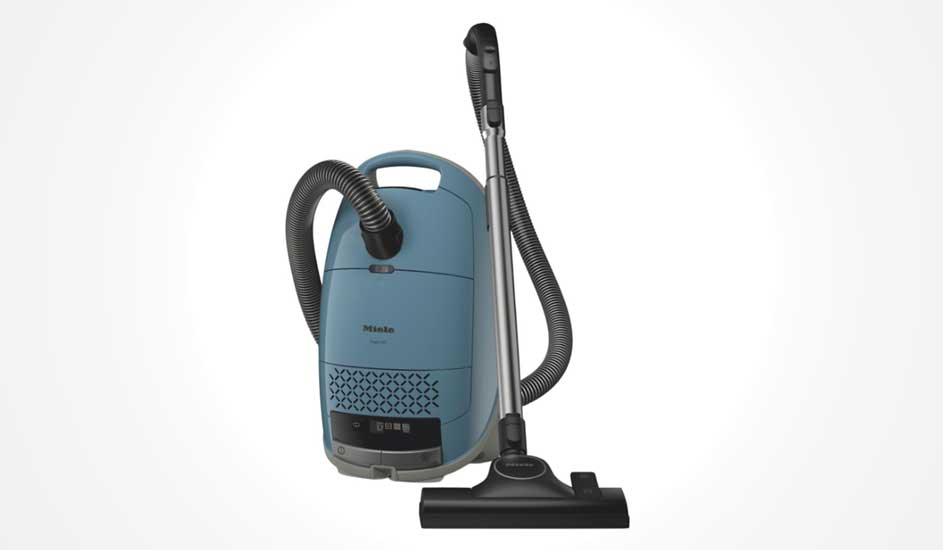 Een blauwe Miele sledestofzuiger staat rechtop, met gebogen slang, zilveren buis en zwarte vloerborstel tegen een witte achtergrond.