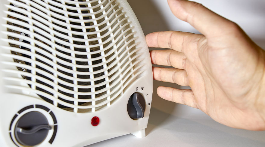 Een witte elektrische kachel met een hand ernaast, beide op een witte achtergrond.