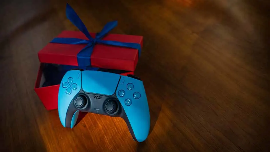 Een blauwe controller ligt voor een rode cadeaudoos met een blauw lint op een houten oppervlak.