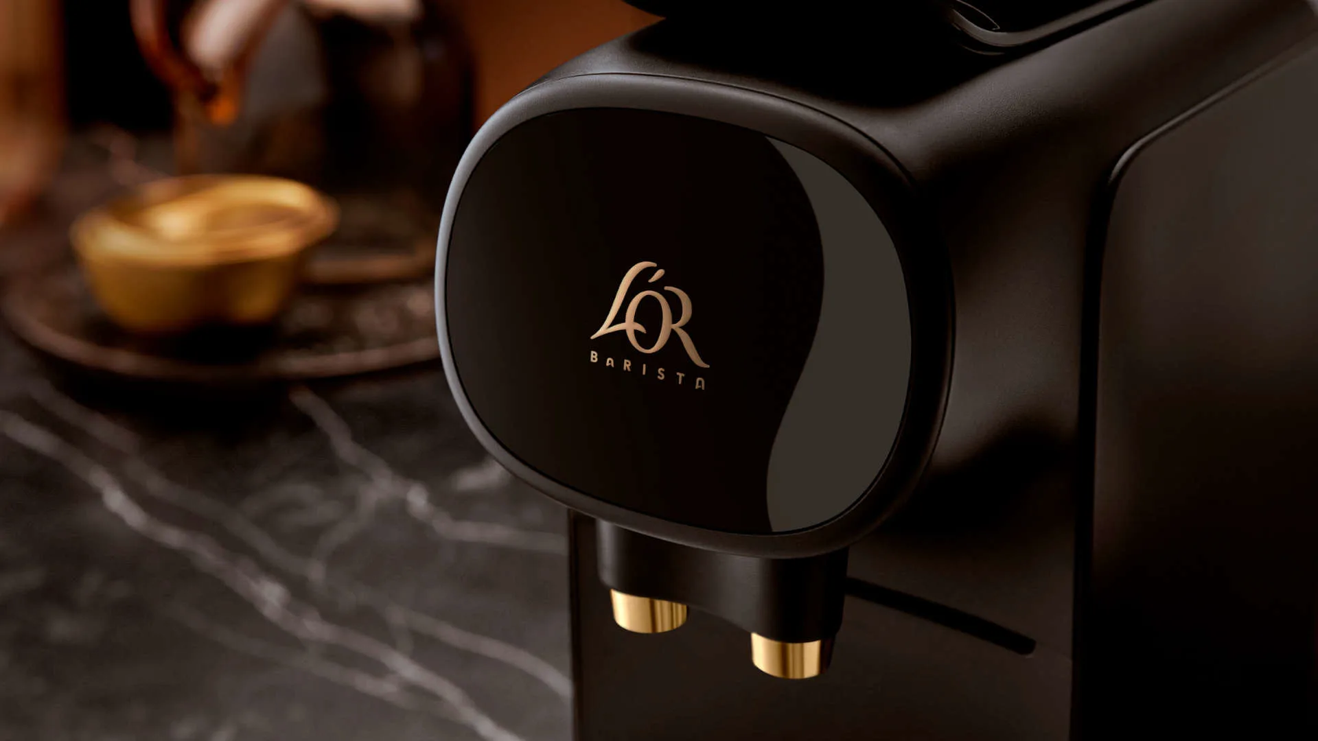 Een zwarte L'OR Barista koffiemachine met gouden details en logo op een marmeren oppervlak.