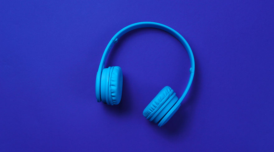 Blauwe koptelefoon ligt op een blauwe achtergrond.