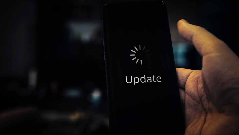Hand houdt een zwarte telefoon vast met de tekst "Update" en een laadicoon op het scherm.
