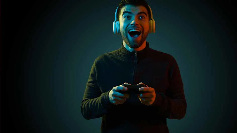 Een man met een koptelefoon en een controller, lachend tegen een donkerblauwe achtergrond met blauwe en oranje belichting.
