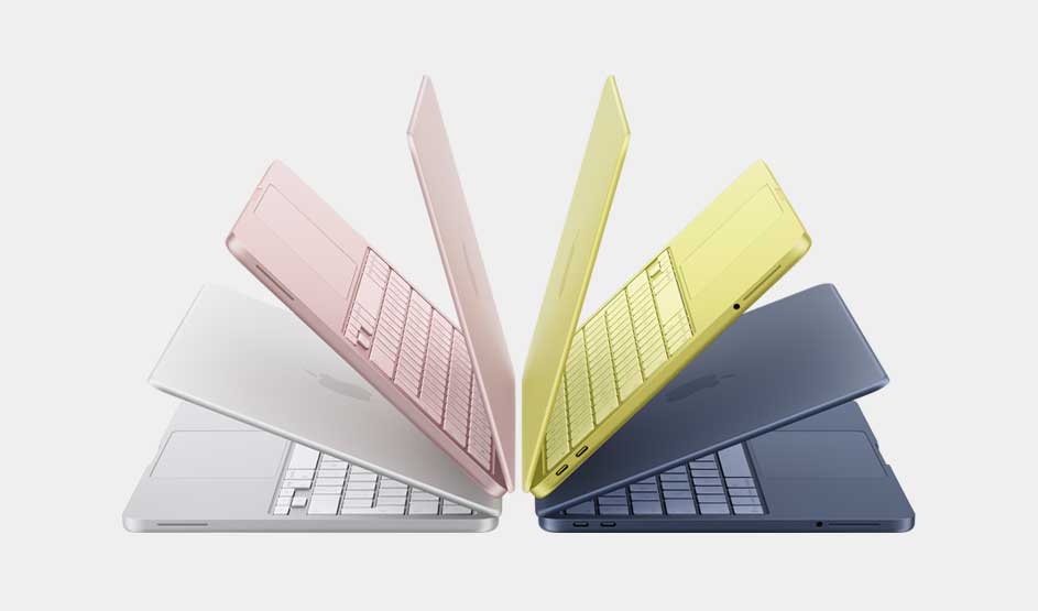 Vier dunne laptops in wit, roze, geel en donkerblauw staan halfopen als een waaier, die hun slanke en kleurrijke ontwerp benadrukt.