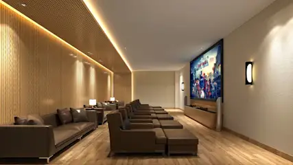 Bruine bioscoopzaal met houten vloer en muren, lange banken en fauteuils gericht op een groot scherm.