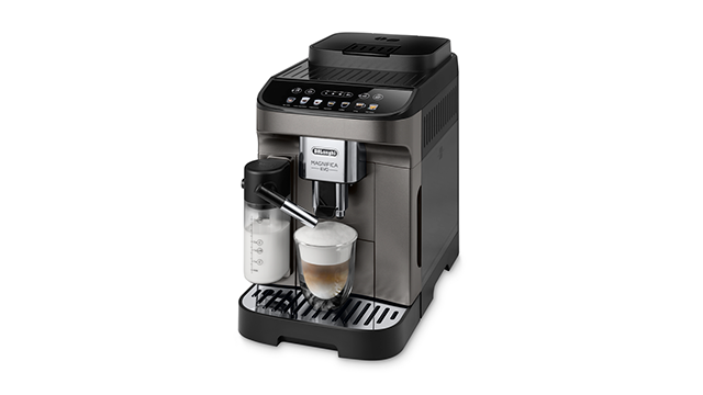 Een grijze De'Longhi koffiemachine met een melkreservoir en een glas koffie op een zwarte basis tegen een witte achtergrond.
