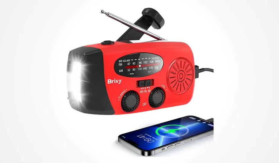 Heldere foto van een rode noodradio met lamp, antenne en handzwengel, die via een kabel een smartphone oplaadt op witte achtergrond.