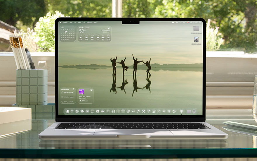 MacBook toont desktop met silhouetten van springende mensen bij water, kalender widget, groene accessoires op bureau. 