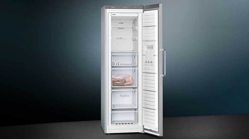 Witte koel-vriescombinatie van ok., open deur, met meerdere legplateaus, transparante lades en een strak, modern ontwerp.