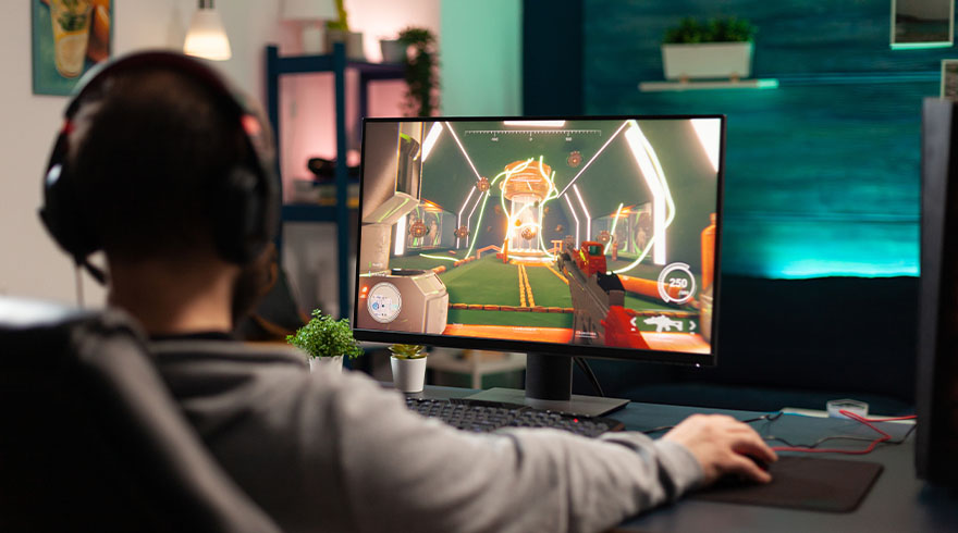 Een persoon met een koptelefoon speelt een videospel op een computerscherm in een kamer.