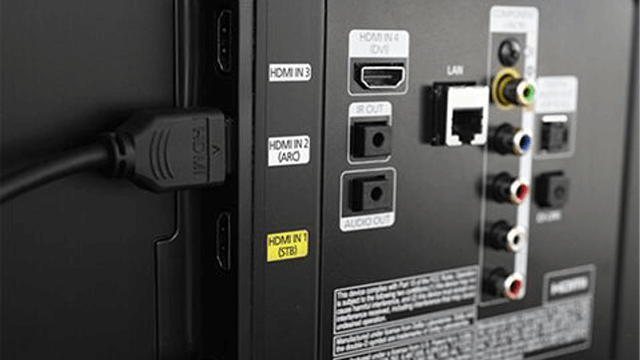 Achterkant van een tv met diverse poorten: HDMI, LAN, audio en video. Een HDMI-kabel is aangesloten.