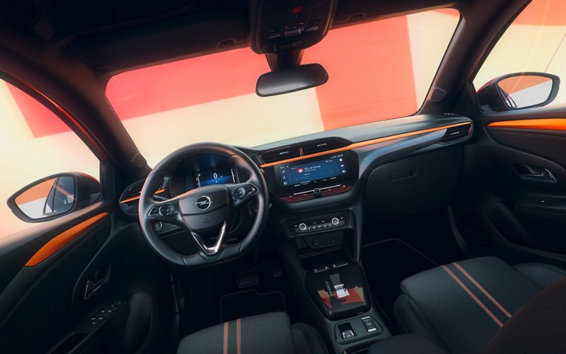 Interieur van een Opel met zwart dashboard, oranje accenten, stuurwiel en touchscreen infotainmentsysteem.