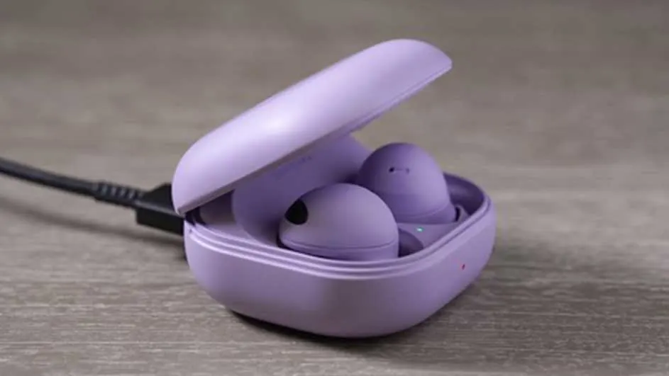 Paarse oortjes in een open oplaadcase met een zwarte kabel op een grijze ondergrond.