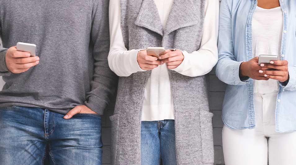 Een groep mensen zit in een cirkel, elk met een smartphone in de hand. Ze dragen kleding in blauwe, rode en beige tinten.