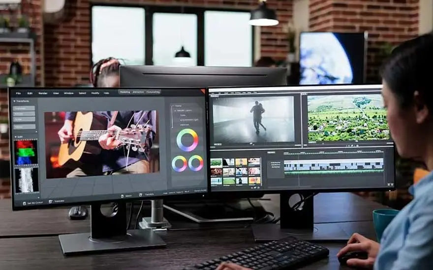 In een creatieve studio monteert iemand video op twee brede schermen, met kleurrijke tijdlijnen, kleurwielen en clips in beeld.