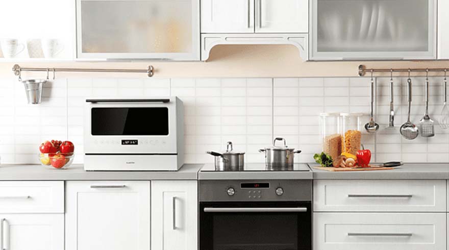 Een keuken met witte kasten, een zilverkleurig fornuis met pannen en een aanrecht met keukengerei en ingrediënten.