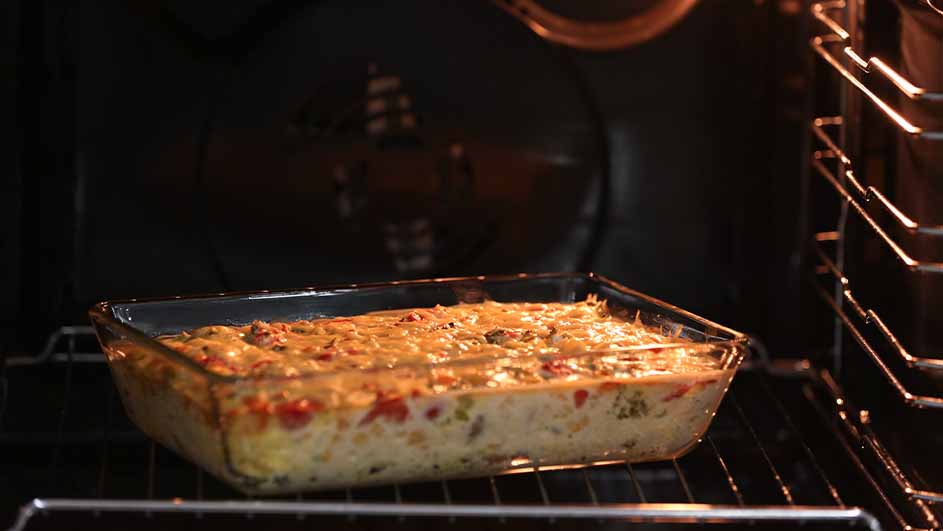 Ovenschaal met een gerecht in een oven. De schaal staat op een rek met metalen ribben in de oven.