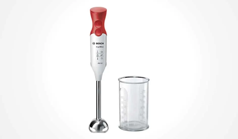 Rood-witte Bosch ErgoMixx staafmixer met roestvrijstalen voet, rechtop naast een doorzichtige maatbeker tegen een lichte achtergrond.