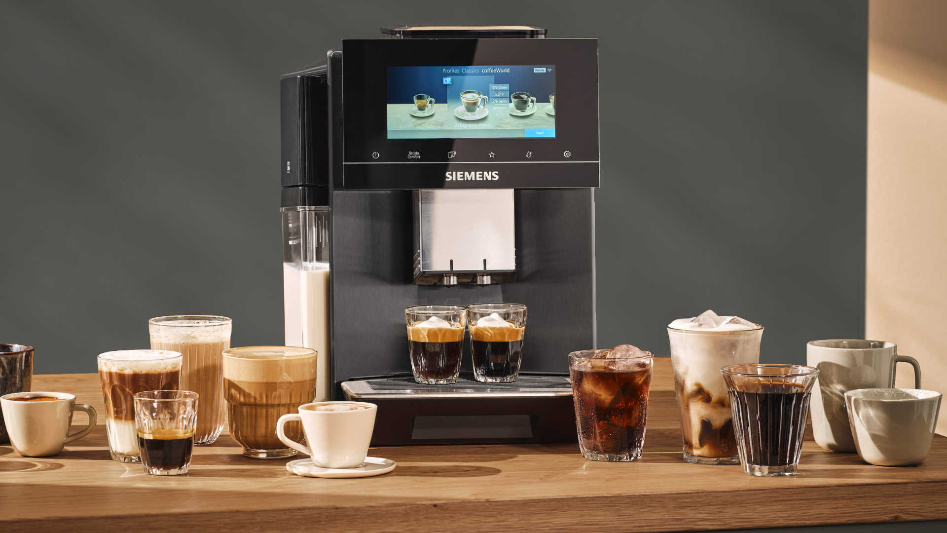 Een koffiezetapparaat staat op een houten tafel, omringd door verschillende soorten koffie in glazen en kopjes.