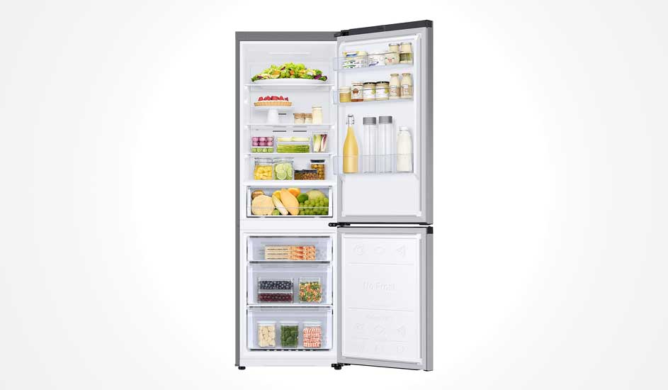 An open fridge filled with fruits, vegetables, bottles, jars, and food items, all organised neatly on shelves and in drawers.
