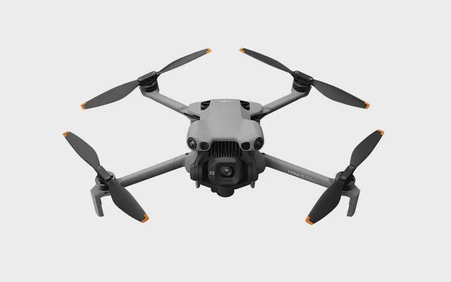 Een vierkante grijze drone met oranje details wordt van bovenaf getoond, op een witte achtergrond met duidelijke lijnen.