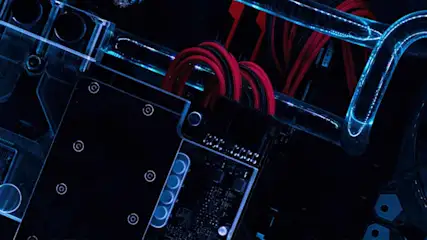 Zicht op interne computeronderdelen met rode kabels en blauwe waterkoelingselementen op een zwarte achtergrond.