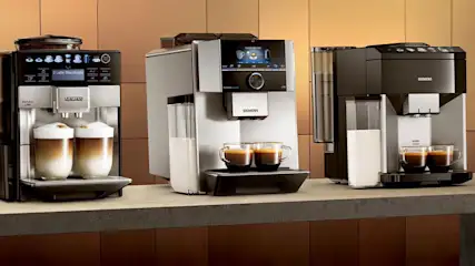 Drie Siemens koffiemachines staan op een aanrecht, waarvan twee met kopjes koffie en één met latte macchiato.