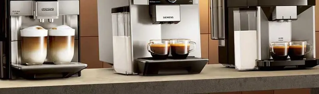 Drie Siemens koffiemachines staan op een aanrecht, waarvan twee met kopjes koffie en één met latte macchiato.