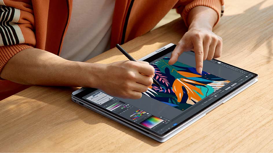 Een persoon gebruikt een stylus en een vinger op een tablet met een ontwerp-app, liggend op een houten tafel.