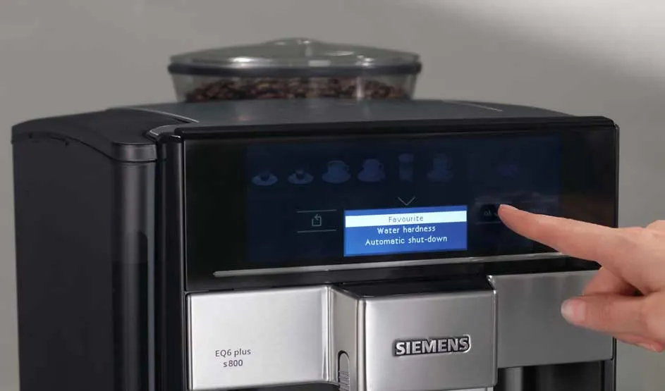 Een zwarte Siemens koffiemachine staat op het aanrecht en schenkt koffie in een glas; koffiebonen zijn zichtbaar in het bonenreservoir.