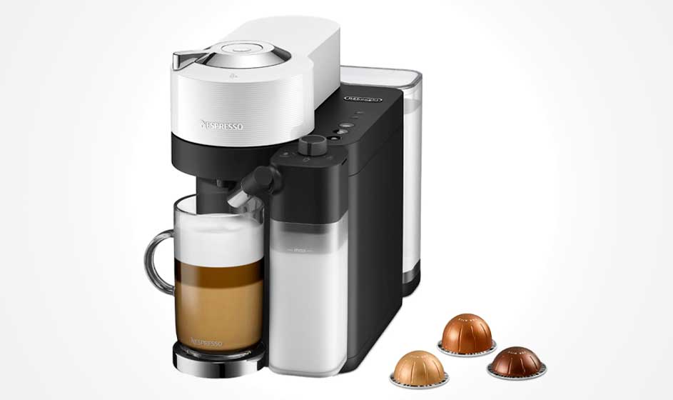 A Nespresso coffee machine with a milk container makes a latte in a glass mug, beside three coffee capsules on a white background.