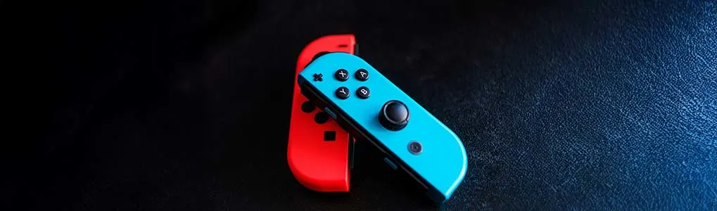 2 Nintendo switch controllers op een donkere achtergrond. 1 van de controllers is blauw en de andere is rood.