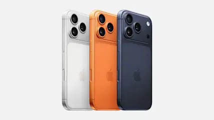 Drie kleuren iPhone 17 Pro Max-toestellen naast elkaar in zilver, oranje en donkerblauw, met afgeronde hoeken en meerdere cameralenzen achterop, op een lichte achtergrond.