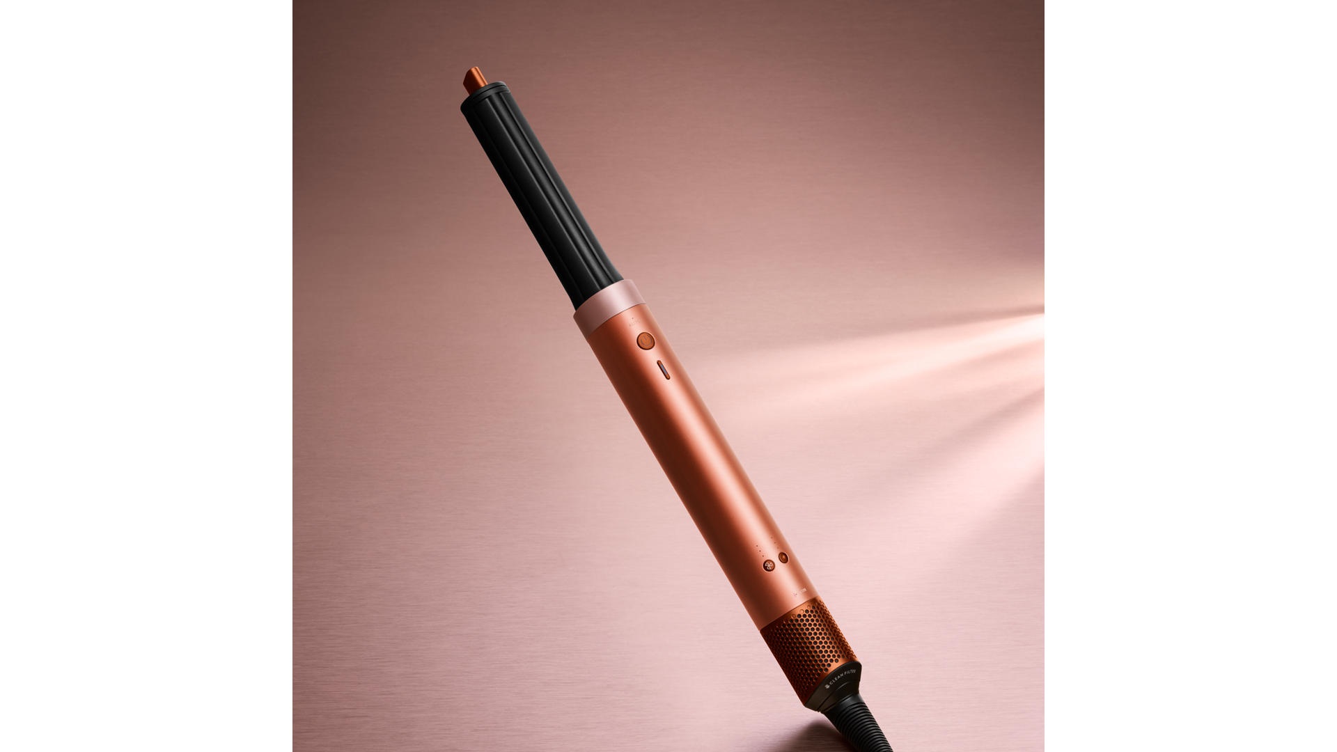 Koperkleurige en zwarte krultang schuin geplaatst op een roze achtergrond.