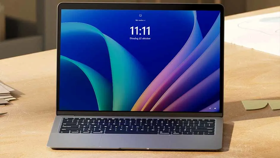 Laptop op een houten bureau met blauw achtergrondscherm, de tijd is 11:11. Op het bureau liggen papieren en plaknotities.