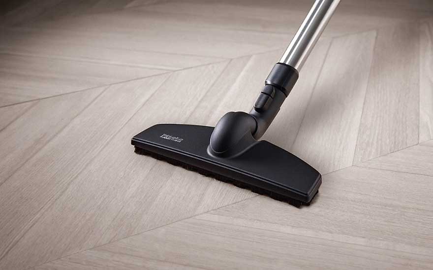 Een parketborstel glijdt zachtjes over een kwetsbare houten vloer en beschermt tegen krassen en slijtage.