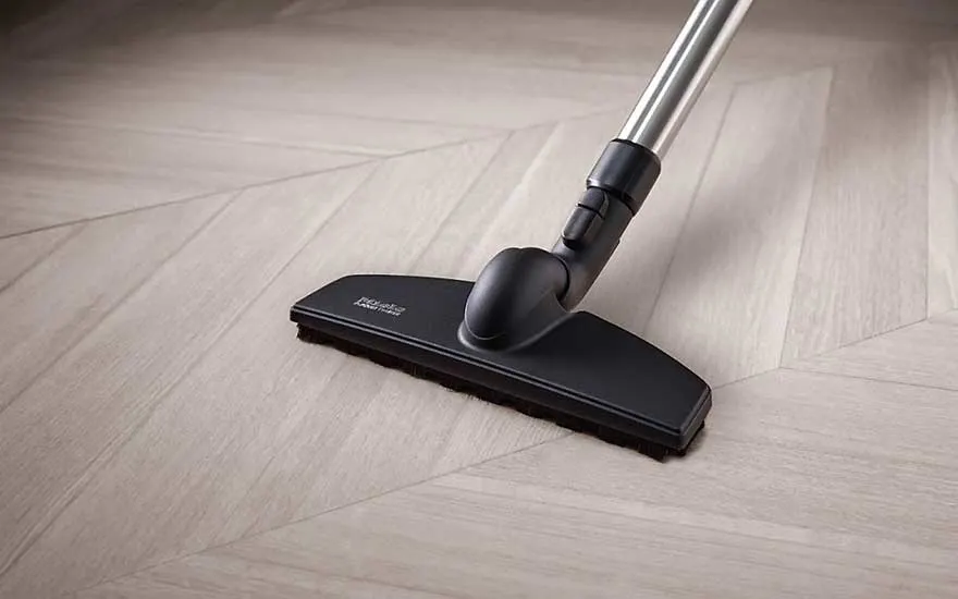 Een parketborstel glijdt zachtjes over een kwetsbare houten vloer en beschermt tegen krassen en slijtage.