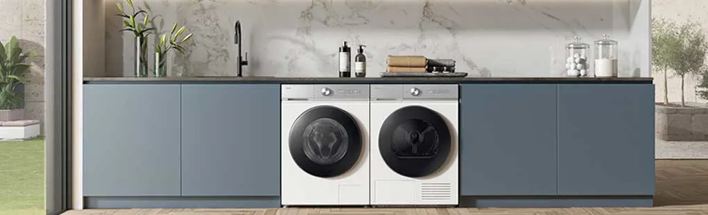 Moderne keuken met blauwe kasten, marmeren achterwand en centraal ingebouwde witte wasmachine en droger naast elkaar.