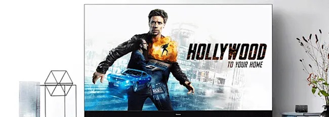 Een grote televisie toont een filmaffiche met een man, auto en de tekst "Hollywood to your home".
