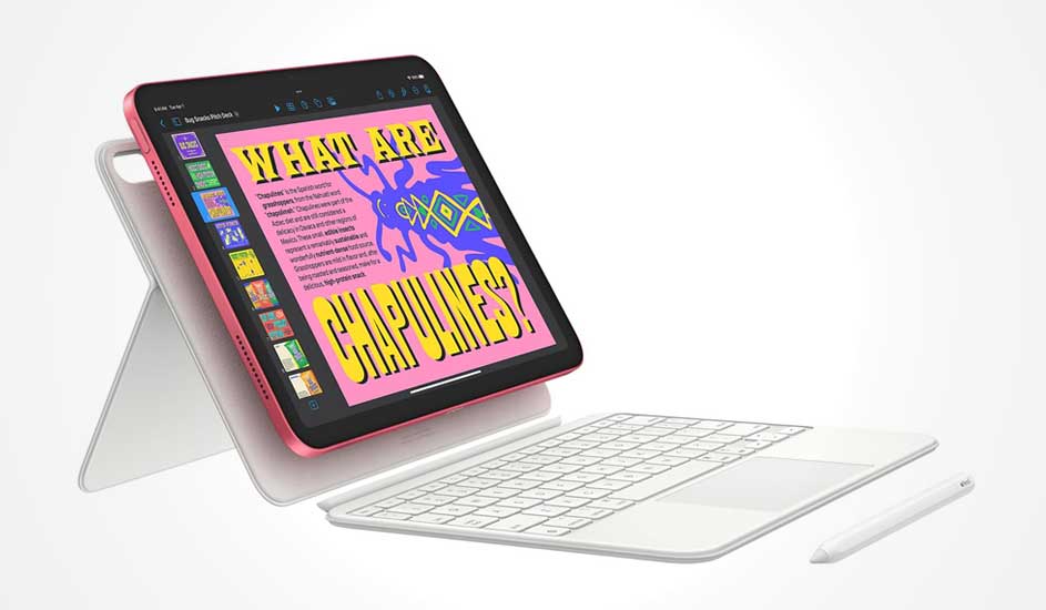 Op de afbeelding zie je een roze Apple iPad met wit toetsenbord en Apple Pencil, rechtopstaand in een standaard met kleurrijk scherm.