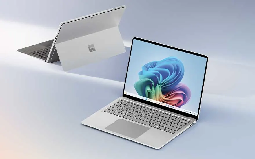 Two sleek Microsoft laptops in a bright studio; one open with a vivid Windows display, one in tablet mode showing the minimalist rear design.