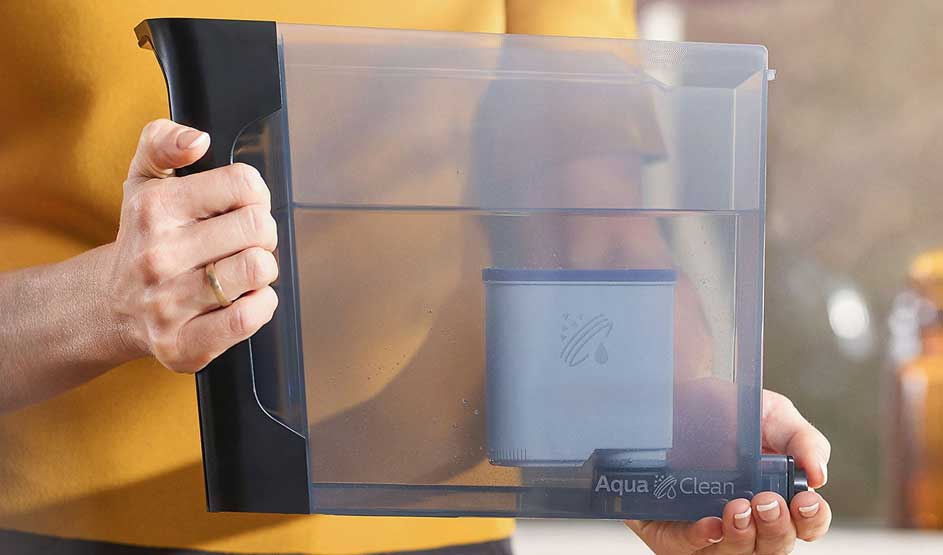 Een persoon houdt een Philips AquaClean-waterreservoir vast met een ingebouwd filter, bedoeld voor koffiemachines.