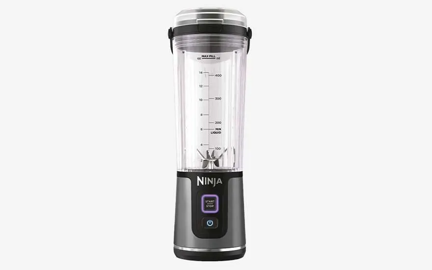 Een draagbare blender met transparante beker, maatverdeling en mesjes staat rechtop op een witte achtergrond.
