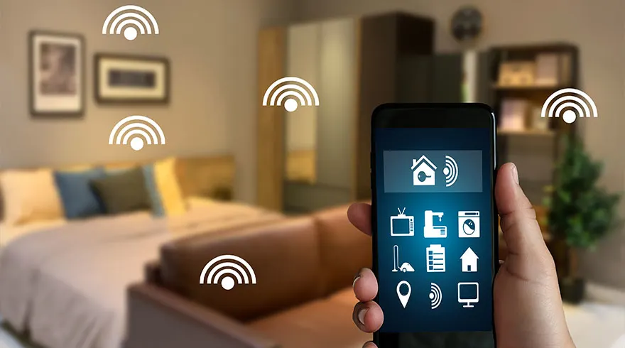 Hand houdt smartphone met smart home app in slaapkamer met bed, kast, plant en wifi symbolen.