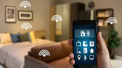 Hand houdt smartphone met smart home app in slaapkamer met bed, kast, plant en wifi symbolen.