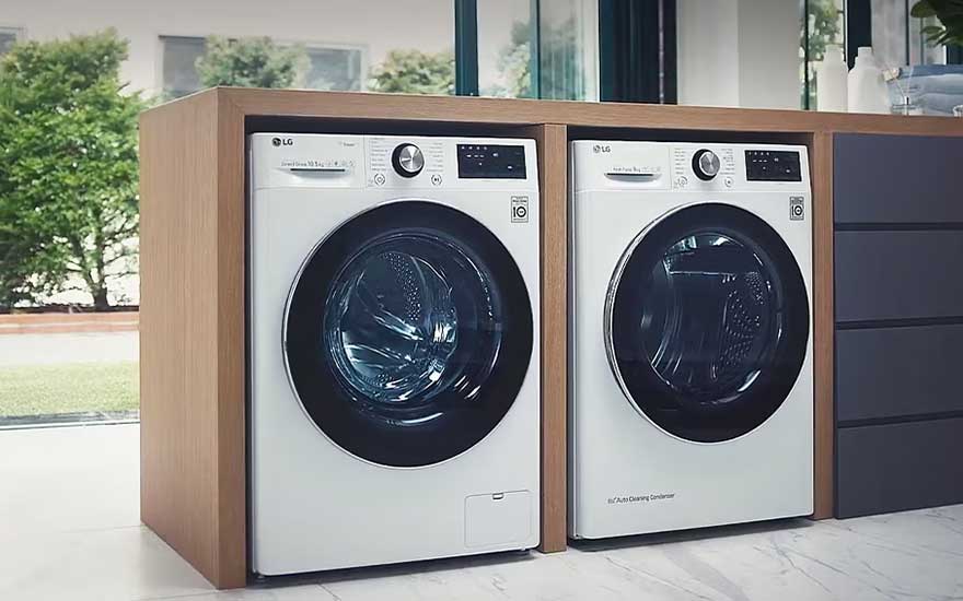 Twee LG-toestellen staan strak ingebouwd in een houten nis, naast donkere laden en grote ramen met uitzicht op groen.