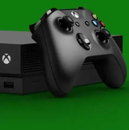 Een zwarte Xbox console met een controller op een groene achtergrond. De console heeft een wit Xbox logo.