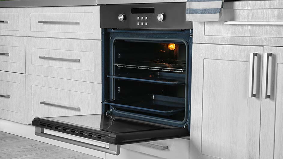 Keuken met witte kasten en een zwarte oven. De ovendeur staat open en er is een licht binnenin zichtbaar.