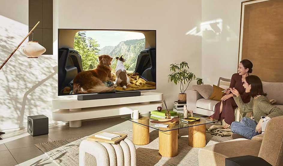 Een modern gezin kijkt ontspannen naar een tv met een hond in een zonnige, stijlvol ingerichte woonkamer.