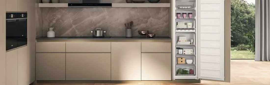 Een openstaande witte koelkaEen keuken met beige kasten, een zwarte oven en een openstaande witte koelkast gevuld met voedsel. Buiten is een tuin zichtbaar.st met zwarte rand, naast houten kastdeuren met zilveren accenten.